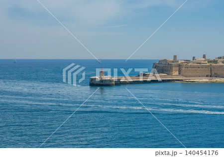 Scenic Mediterranean seascape with red lighthouse, historic limestone fortress, sailing boats and turquoise sea under bright blue sky at Grand Harbour Malta High quality photo Scenic Mediterranean seascape with red lighthouse, historic limestone fortress, sailing boats and turquoise sea under bright blue sky at Grand Harbour Malta High quality photo 140454176