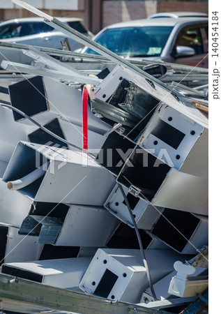 Pile of discarded white metal cabinets and sheet metal boxes stacked for recycling at scrap yard with parked cars in background 140454184