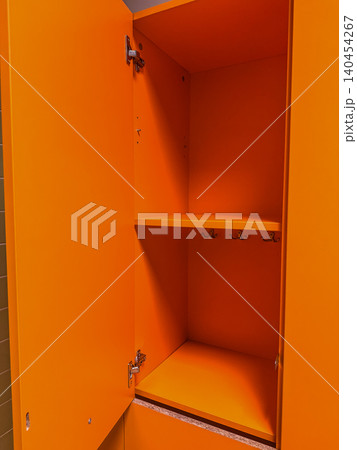 Bright orange open empty locker cabinet with inner shelves and metal hooks in a modern gym, school, or workplace changing room. Bright orange open empty locker cabinet with inner shelves and metal hooks in a modern gym, school, or workplace changing room. 140454267