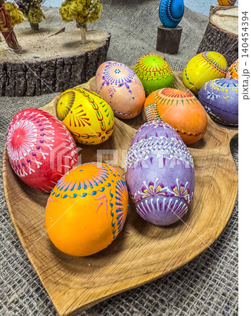Colorful Hand-Painted Easter Eggs with Intricate Traditional Ornaments in a Wooden Plate, Rustic Spring Holiday Decoration Colorful Hand-Painted Easter Eggs with Intricate Traditional Ornaments in a Wooden Plate, Rustic Spring Holiday Decoration 140454394