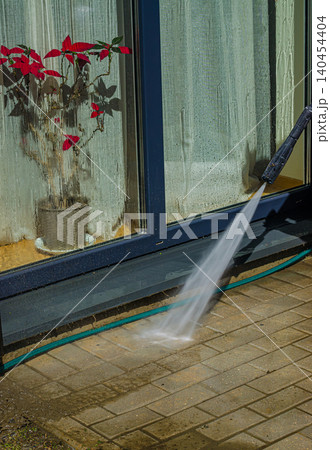 Home Exterior Maintenance: Pressure Washing Dirty Stone Pavement Tiles on an Outdoor Terrace with a High-Power Water Jet Spray Home Exterior Maintenance: Pressure Washing Dirty Stone Pavement Tiles on an Outdoor Terrace with a High-Power Water Jet Spray 140454404