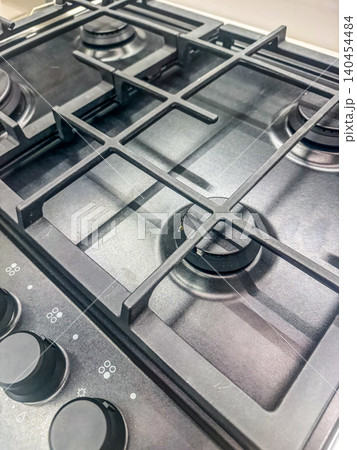 Modern Black Gas Stovetop with Cast Iron Grates and Control Knobs, Close-up of Clean Kitchen Cooktop Appliance 140454484