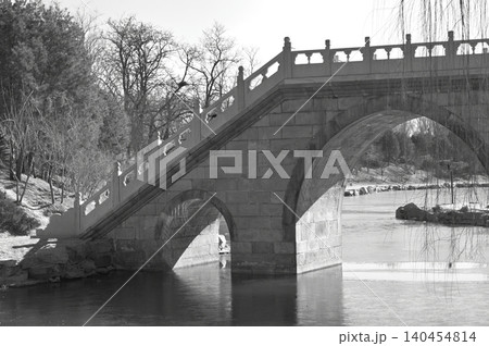 Black and white stone bridge over a calm park lake Black and white stone bridge over a calm park lake 140454814