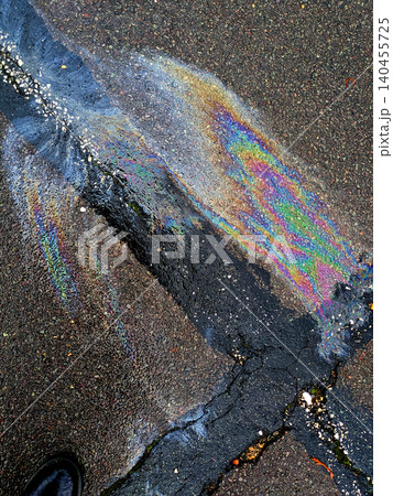 A leaked Car Oil Petrol in The Rain on a Tarmac Road Metallic Rainbow 140455725