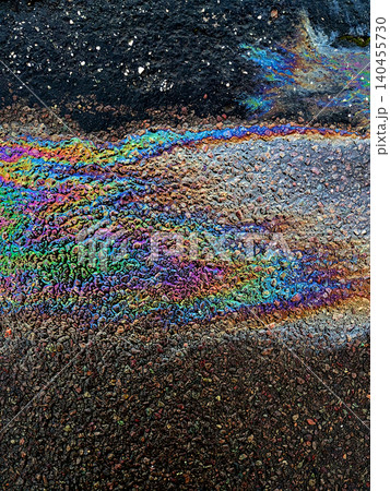 A leaked Car Oil Petrol in The Rain on a Tarmac Road Metallic Rainbow 140455730