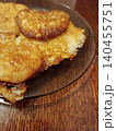 Golden brown potato pancakes, also known as latkes or draniki, fresh from frying and arranged on a dark plate, resting on a textured wooden table 140455751