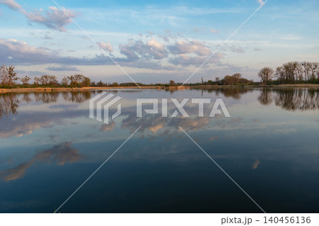 Reflection of clouds in the water of a calm lake Reflection of clouds in the water of a calm lake 140456136