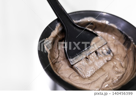 A brush in a container of hair dye A brush in a container of hair dye 140456399