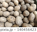 Freshly harvested raw unpeeled potatoes forming a large pile, showing organic root vegetables with natural dirt on skin, ready for cooking or processing 140456423