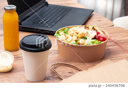 work at home on a laptop, there is food on the table, salad, coffee and juice, delivery, there are no people, work at home on a laptop, there is food on the table, salad, coffee and juice, delivery, there are no people, 140456706