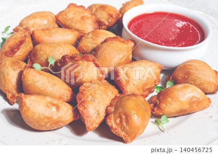 Fried mini chebureks, with sauce, on a decorative plate, hard light, no people, Fried mini chebureks, with sauce, on a decorative plate, hard light, no people, 140456725