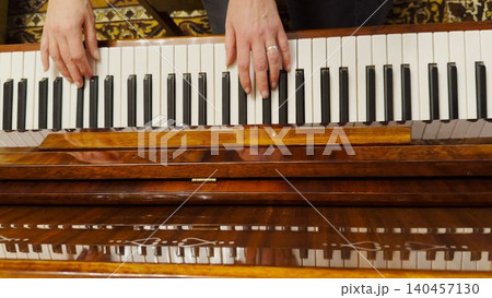 Top view of adult female hands playing gentle piece of classical music on brown piano. Scene captures the movement, rhythm and elegance of performance, highlighting beauty of live instrumental play Top view of adult female hands playing gentle piece of classical music on brown piano. Scene captures the movement, rhythm and elegance of performance, highlighting beauty of live instrumental play 140457130