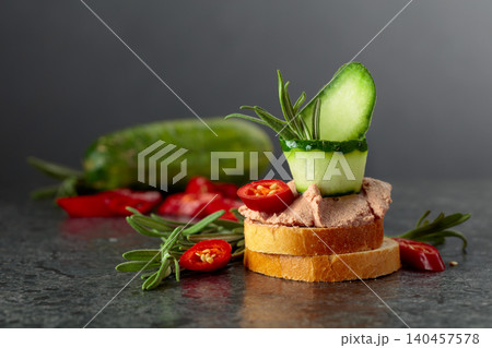 Bread slices with pate, cucumber, red pepper, and rosemary. Bread slices with pate, cucumber, red pepper, and rosemary. 140457578