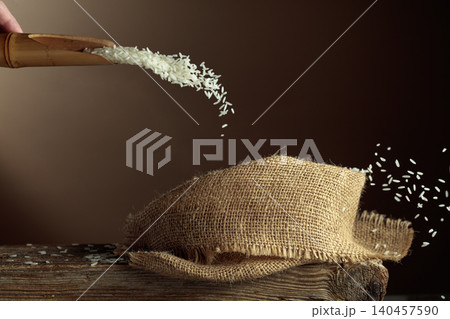Rice is poured into a burlap bag. Rice is poured into a burlap bag. 140457590