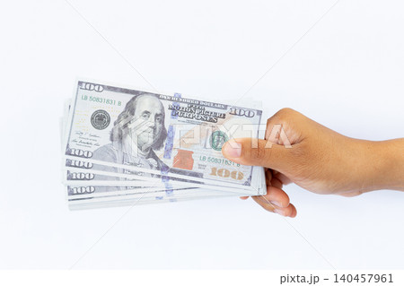 Hand holds crisp hundred-dollar bills against a clean white background. Fingers gently grip the stack, showing careful handling. No emotion visible, focus remains on the money's detail and texture Hand holds crisp hundred-dollar bills against a clean white background. Fingers gently grip the stack, showing careful handling. No emotion visible, focus remains on the money's detail and texture 140457961