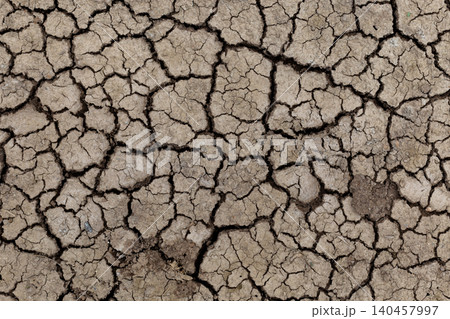 Cracked earth reveals dry, brittle soil. Deep fissures spread across the parched surface. Color shifts from beige to darkened cracks. Texture shows erosion and aridity's force Cracked earth reveals dry, brittle soil. Deep fissures spread across the parched surface. Color shifts from beige to darkened cracks. Texture shows erosion and aridity's force 140457997