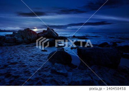 huge stones on a sandy beach at night. wonderful summer vacation season at the black sea. full moon over calm waves washing the sand shore. mysterious nature background with cloudy sky 140458458