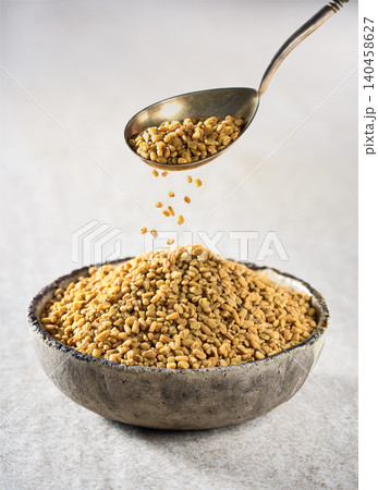 Fenugreek seeds on beige background Fenugreek seeds on beige background 140458627