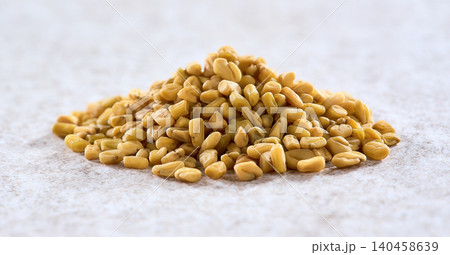 Heap of fenugreek seeds on beige background Heap of fenugreek seeds on beige background 140458639