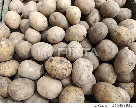 Freshly harvested earthy potatoes displaying natural dirt and imperfections, filling the frame and representing organic farming, healthy eating, and a bountiful crop harvest Freshly harvested earthy potatoes displaying natural dirt and imperfections, filling the frame and representing organic farming, healthy eating, and a bountiful crop harvest 140458930