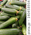 Fresh green cucumbers piled high in a retail bin, showcasing healthy, organic produce for sale, representing nutrition, vegetarian food, and market abundance 140458934