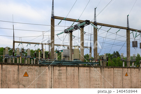 Electrical substation and high voltage power grid infrastructure behind concrete wall, distribution station under cloudy sky Electrical substation and high voltage power grid infrastructure behind concrete wall, distribution station under cloudy sky 140458944
