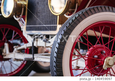Closeup view of an antique automobile with brass headlights, vintage radiator, and whitewall tire details. Historic retro transportation vehicle displayed in a classic car museum with elegant early Closeup view of an antique automobile with brass headlights, vintage radiator, and whitewall tire details. Historic retro transportation vehicle displayed in a classic car museum with elegant early 140459097