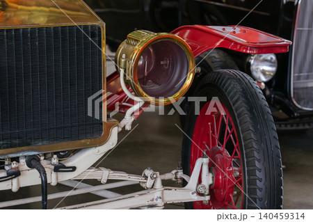 Vintage automobile with brass headlight and red fender in museum setting Vintage automobile with brass headlight and red fender in museum setting 140459314