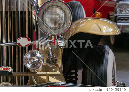 Vintage car showcases elegant front grille and chrome accents in exhibition hall. Nostalgic atmosphere enhanced by bright indoor lighting and classic design elements. Vintage car showcases elegant front grille and chrome accents in exhibition hall. Nostalgic atmosphere enhanced by bright indoor lighting and classic design elements. 140459340