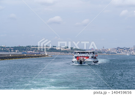 A tour boat navigates the waters of the Bosphorus strait, with a stunning skyline featuring historic buildings and a vibrant atmosphere on a sunny day. A tour boat navigates the waters of the Bosphorus strait, with a stunning skyline featuring historic buildings and a vibrant atmosphere on a sunny day. 140459656