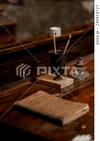 A rustic desk displays a vintage ink pot, brushes, and a worn book, capturing a nostalgic atmosphere and a sense of creativity and history. 140459727