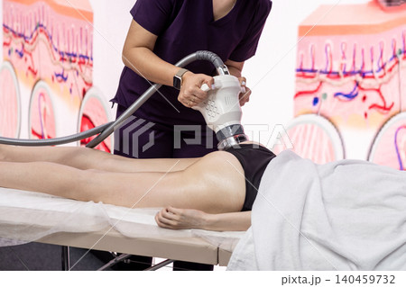 A professional uses advanced equipment for body contouring on a clients thigh in a modern clinic, showcasing the latest aesthetic techniques. 140459732