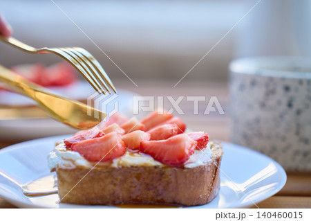 French toast with strawberries and honey served on plate with fork and knife French toast with strawberries and honey served on plate with fork and knife 140460015