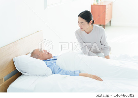 寝たきりの高齢者を看病する女性 寝たきりの高齢者を看病する女性 140460302