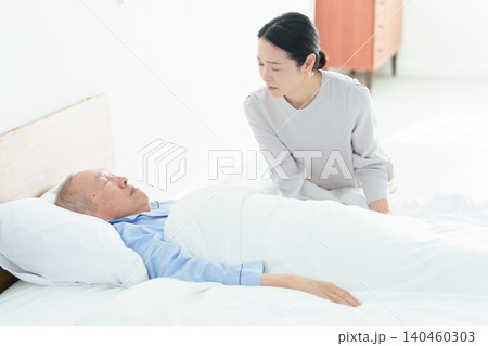 寝たきりの高齢者を看病する女性 寝たきりの高齢者を看病する女性 140460303