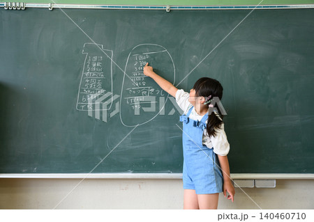 黒板の時間割の前で発表する女子小学生 黒板の時間割の前で発表する女子小学生 140460710