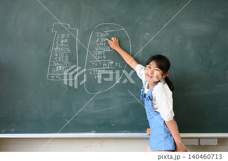 黒板の時間割の前で発表する女子小学生 140460713