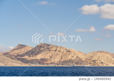 Coastal mountains rise dramatically above tranquil waters under a bright sky, highlighting the beauty of remote natural landscapes. Coastal mountains rise dramatically above tranquil waters under a bright sky, highlighting the beauty of remote natural landscapes. 140460942