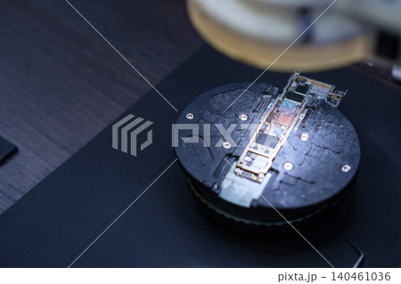 A microscope is focused on a black circular surface showing various circuits and technology parts during working hours in a laboratory. A microscope is focused on a black circular surface showing various circuits and technology parts during working hours in a laboratory. 140461036