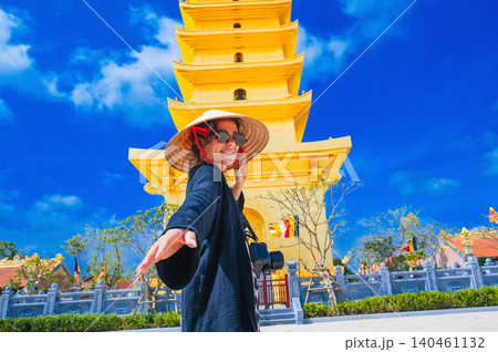 happy tourist woman at the golden tower on Vietnamese Buddhist pagoda Truc Lam Phung Thuy Son in Nha Trang in Vietnam. Travel, tourism and sightseeing in Asia happy tourist woman at the golden tower on Vietnamese Buddhist pagoda Truc Lam Phung Thuy Son in Nha Trang in Vietnam. Travel, tourism and sightseeing in Asia 140461132