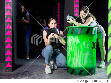 Girls play laser tag, jokingly fight with light weapons Girls play laser tag, jokingly fight with light weapons 140461581