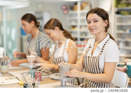 Three craftsperson are busy sculpting from clay and painting ceramic products Three craftsperson are busy sculpting from clay and painting ceramic products 140461698