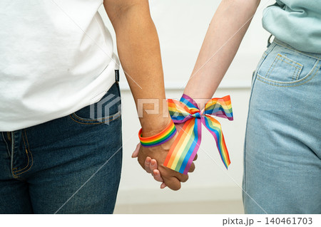 Asian LGBT couple woman holding hand wearing rainbow wristband. 140461703