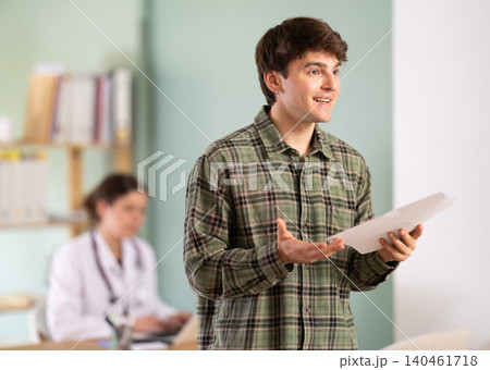 Happy young guy patient leaving medical office after doctor appointment holding prescription in hands in medical center 140461718