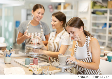 Teenage girl sculpts ceramic cup in workshop 140461742