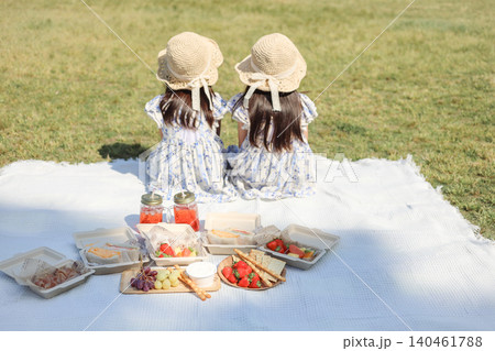 公園でピクニックを楽しむ姉妹の後ろ姿とランチタイムの風景 公園でピクニックを楽しむ姉妹の後ろ姿とランチタイムの風景 140461788
