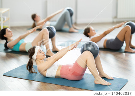 Young girl doing press with softball band between legs lying on the floor 140462037