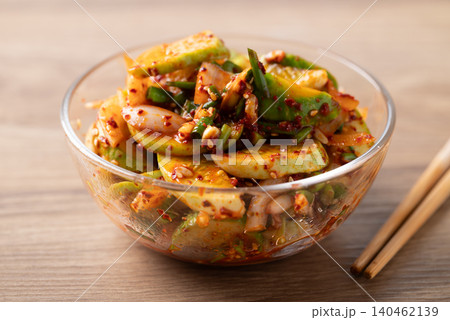 Korean cucumber salad in a glass bowl and chopsticks on wooden background 140462139