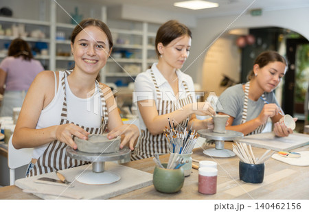 Woman teacher and students sculpt and paint ceramics Woman teacher and students sculpt and paint ceramics 140462156