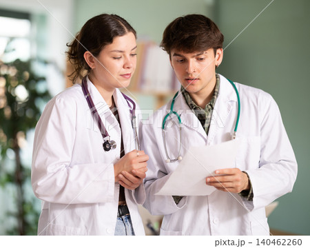 Two young doctors are standing in the office and discussing tests. 140462260